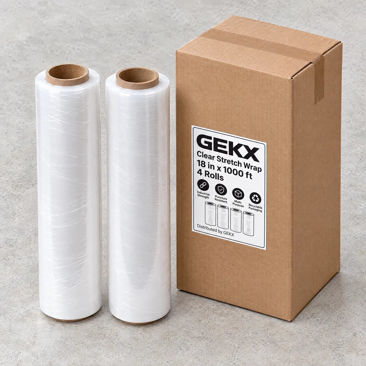 Two GEKX clear stretch wrap rolls standing next to a closed GEKX shipping box on light concrete